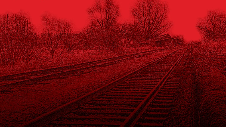 Uz afišas sarkanā fona tālumā aizvijas vilciena sliedes