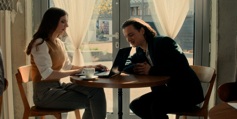 Puisis un meitene sēž kafejnīcā un skatās datorekrānā