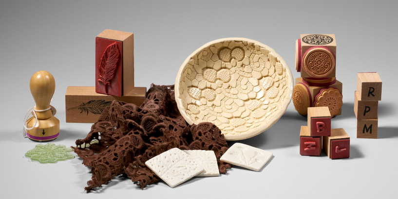 Foto kompozīcija no darbnīcā izmantojamiem materiāliem, spiedogiem, audumiem un gatavais trauks