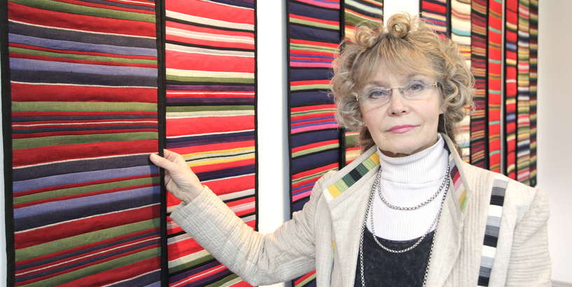 Mākslinieces foto pret slokšņveida gobelēnu darbiem