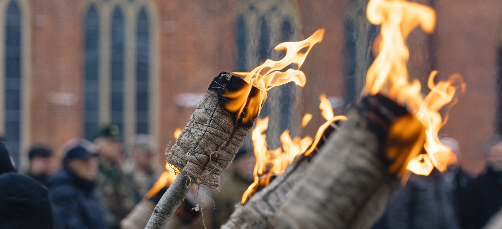 Degošas lāpas uz Rīgas doma sarkano ķieģeļu fona